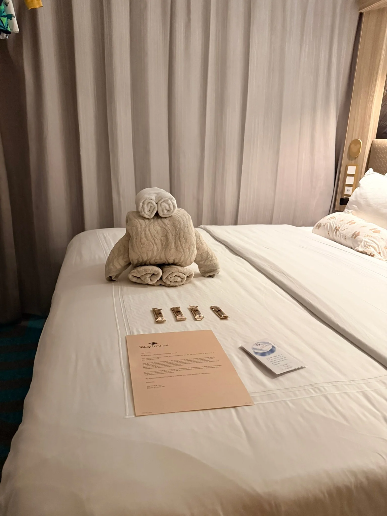 Our bed after the nightly turndown, with a towel animal and four Sweet Dreams chocolates.