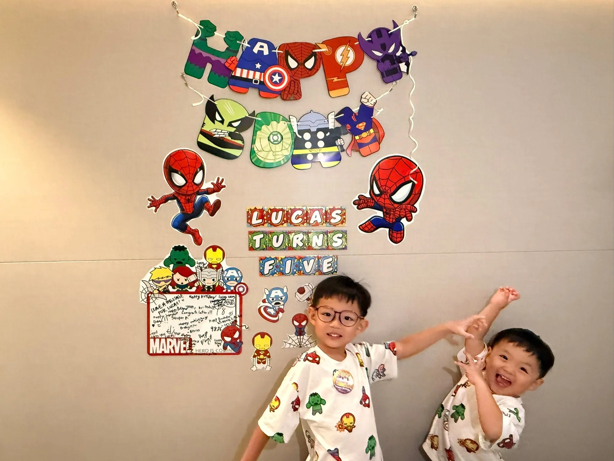 Lucas and Ethan in front of the birthday decorations and a whiteboard full of messages.