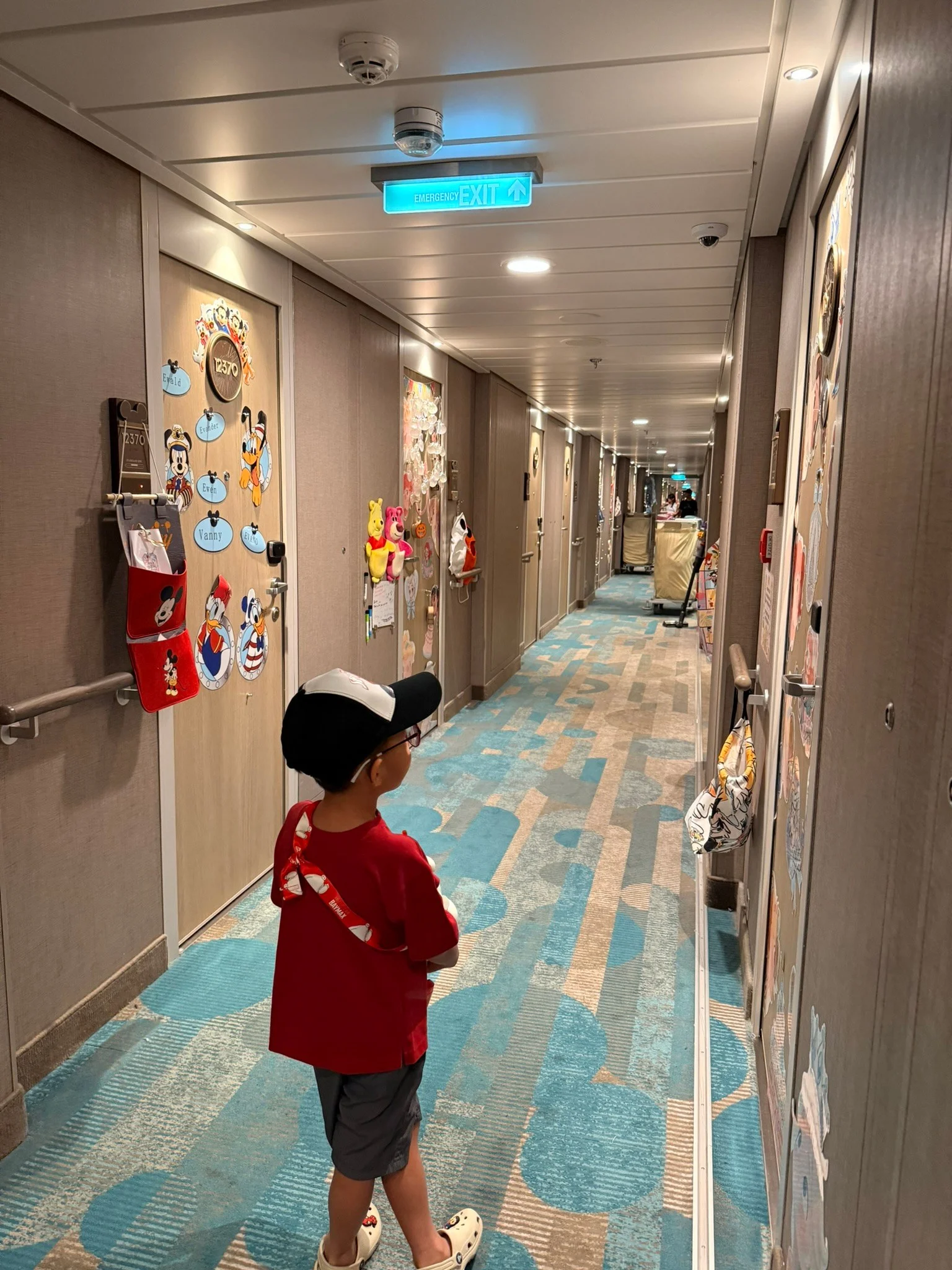 Lucas walking down the stateroom corridor, choosing a door to leave a Pixie Dust gift.