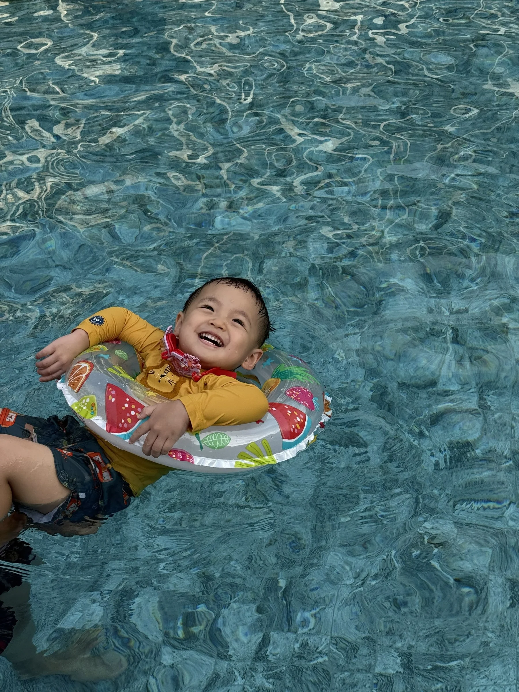 Ethan smiling while floating in the swimming pool with his colourful swim ring.